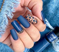 a woman's hand with blue nail polish and leopard print on the tip of her finger