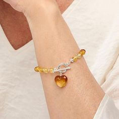 Amber Extraordinaire Beaded Heart Drop Toggle Bracelet  Bold and aglow, the heart-shaped amber dangling from this beaded bracelet is a stunning way to wear your love for the ancient tree resin. Treat yourself to a wonder of the gemstone world.        S/M approx. 6-3/4"L; fits 6-3/4" wrist     M/L approx. 7-1/4"L; fits 7-1/4" wrist      Approx. 1/4"W     Stamped .925 sterling silver; polished finish      Amber bead and sterling silver bead bracelet: toggle clasp    Stone Information       All siz Elegant Amber Bracelets With Polished Beads, Adjustable Amber Bracelet With 8mm Beads, Adjustable Amber Hand-strung Beaded Bracelets, Handmade Heart-shaped Amber Jewelry, Amber Multi-strand Jewelry With Gemstone Beads, Earth Bracelet, Beaded Heart, Sterling Silver Bead Bracelet, Amber Bracelet