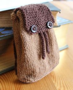 a brown knitted bag sitting on top of a wooden table next to a stack of books