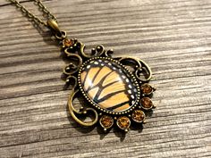 a necklace with a butterfly on it sitting on top of a wooden table next to a chain