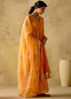 Features a tangerine front open silk anarkali embellished with zari & patra work, finished with gota lace & button detailing on the front. Completed with a matching sharara with lace detailing and an embellished dupatta. Composition : Anarkali & Sharara: Chanderi Silk Lined with Mul Cotton, Dupatta: Organza Care: Dry Clean Only and Vacuum Storage All products can be customised for sleeves, length of blouse and neck design Delivery : 3-4 weeks as the product is hand crafted. Check Size Guide or choose MySize for free customisation (All Sizes above XL can be made at 15% additional cost) For more information and sizes please contact fabiliciousfashion@gmail.com or visit our Copenhagen studio.