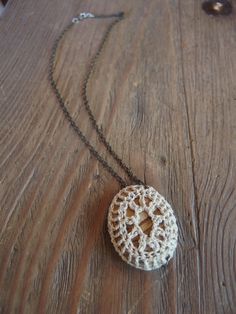 a white crocheted pendant on a wooden table