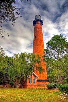 a red light house surrounded by trees on a cloudy day