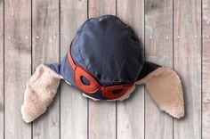 a stuffed animal wearing a hat on top of a wooden floor next to a pair of sunglasses