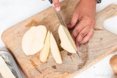 a person cutting apples on a wooden cutting board