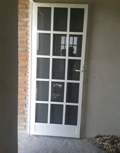 an open door in front of a brick wall with glass panes on the side