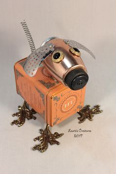 a metal dog head sitting on top of an orange box with a comb in it's mouth