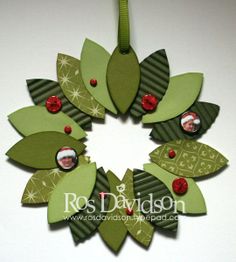 an ornament made out of green paper with leaves and red berries on it