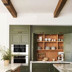 a kitchen with green cabinets and marble counter tops