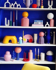 the shelves are filled with colorful vases and other decorative items on display in this blue room