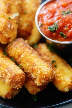 some fried food on a black plate with dipping sauce