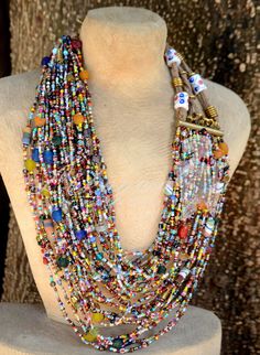 This Multi-colored layered African necklace is soothingly beautiful.This Masai beaded  layered necklace is for the stylish lady who loves color and pomp. The colors are inviting.A rich mixture of hand-painted Segi beads,Masai beads alongside Gas beads made from bottles.The beauty is you can also adjust it due to the extra links on the clasp. This repurposed jewelry makes the perfect gift for her. You can match it up with a simple pair of earrings.The distance from the clasp to the first strand i Artisan Multicolor Multi-strand Beads, Artisan Multicolor Multi-strand Beaded Necklaces, Multicolor Beaded Multi-strand Layered Necklace, Bohemian Multicolor Beaded Layered Necklace, Multi-strand Beaded Necklace With Large Beads, Multicolor Multi-strand Beads For Jewelry Making, Bohemian Multicolor Double Strand Layered Necklace, Bohemian Multicolor Layered Necklace With Round Beads, Multicolor Double Strand Bohemian Layered Necklace