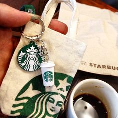 a starbucks keychain sitting next to a cup of coffee