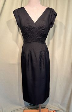 This is a gorgeous vintage dress from the 50s or early 60s. Label reads, Semont, New York. No size tags. The bust measures 36", waist 28", hip 38", see measurements below.  Made of a solid black, rayon I believe. The dress has wide straps that form a slight cap sleeve over the shoulder. Tea length with a full skirt with kick pleat under the wide skirt drape in back. The waist band is a wide yoke of pin pleats. The bodice has built-in satin cups. The neckline is a deep V in front & a deeper V in Mid-century Style Fitted Lined Dress, 1950s Style Dresses With Pleated Fitted Bodice, Vintage Fitted Dress With Pleated Waist, Mid-century A-line Fitted Dress, Skirt Drape, 1950s Style A-line Dress With Box Pleat, Skirt Draping, Wide Skirt, Back Skirt