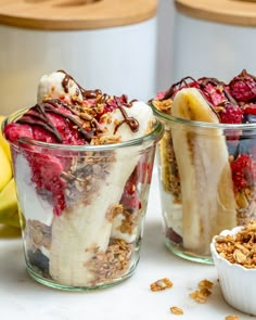 two glass cups filled with granola and banana's, raspberries, and yogurt