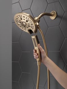 a person is holding the shower head in their hand