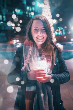 a woman is holding a lantern in her hands and smiling at the camera while standing outside