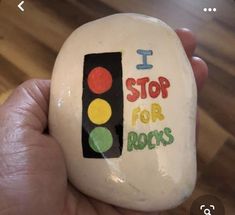 a hand holding a painted rock that says i stop for rocks with a traffic light on it