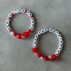 two red and white bracelets sitting on top of a cement floor next to each other