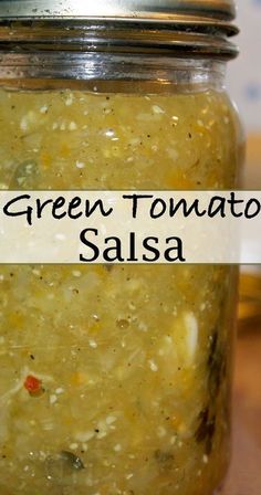 a jar filled with green tomato salsa on top of a wooden table