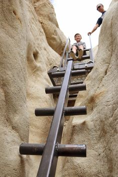 two men are climbing up the side of a mountain with metal bars attached to it