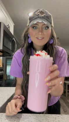 a woman holding a pink drink in her hand