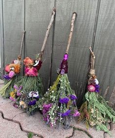 flowers are arranged on the ground next to a wooden fence with sticks sticking out of it