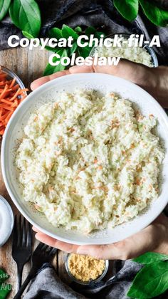 two hands holding a bowl of mashed potatoes with carrots and parsley on the side