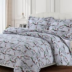 a bed covered in a white comforter with christmas trees on the sheets and pillows