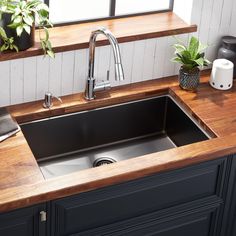 a kitchen sink with wooden counter top and bowl of fruit on the counter next to it