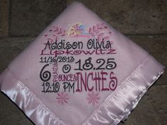 a pink graduation cap with the date and year embroidered on it, sitting on a tile floor