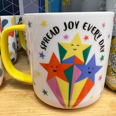 two colorful coffee mugs sitting next to each other on a wooden table with donuts in the background