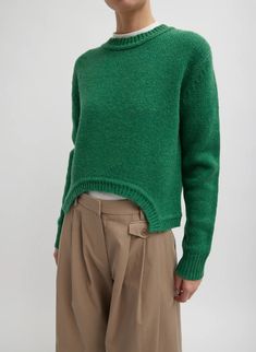 a woman wearing a green sweater and tan pants