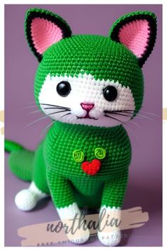 a crocheted green and white cat sitting on top of a table