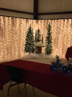 a table with a red cloth on it and christmas decorations in front of the curtain