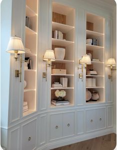 a white bookcase with two lamps on each side and some books in the back