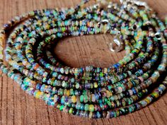 multicolored glass beaded necklace with silver clasps on wooden surface, close up