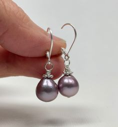 Lavender Pearl Earrings. Sterling Silver Leverback Earrings. The earrings are handmade using Edison freshwater pearls (nucleated) and sterling silver components. These gorgeous pearls are lavender in color with great luster and silvery to pink overtones. The pearls are natures' creations and are little differences are seen in color and shape; they are a short teardrop shape and ~9.3 mm wide. The earrings, accented by sterling silver Bali daisies and mounted with simple leverback earring wires, measure 1 1/4 inches (3.1 cm) long. Pearl is a June birthstone. Pictures are enlarged to show detail. You will receive a remake of these beautiful lavender Edison pearl precious metal leverback earrings made with the same quality materials and attention to detail. The earrings ship in a small organza Pearl Drop Earrings Gift, Pearl Drop Earrings For Gift, Drop Pearl Earrings With Ear Wire For Gift, Purple Pearl Earrings For Pierced Ears As A Gift, Purple Pearl Earrings Gift, Elegant Lavender Earrings With Ear Wire, Purple Pearl Earrings As Gift, Purple Pearl Earrings For Gift, Elegant Nickel-free Lavender Earrings