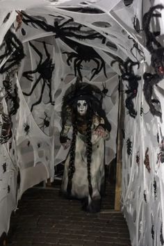 a person dressed in white and black is walking through a tunnel with spider webs on the walls