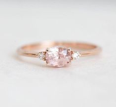 a pink diamond ring with three diamonds on the band and an oval stone in the center