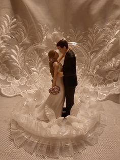 a wedding cake topper with a bride and groom kissing