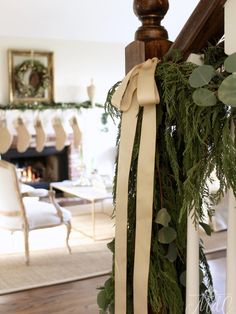 a christmas garland hanging on the banister in a living room with chairs and fireplace