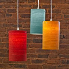 three different colored lamps hanging from a brick wall