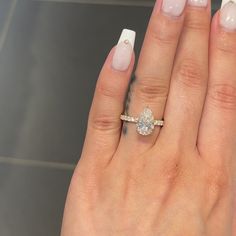 a woman's hand with a diamond ring on it and white nail polishes