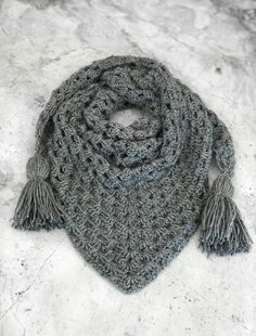 a gray crochet scarf with tassels on the ends and an inscription that reads