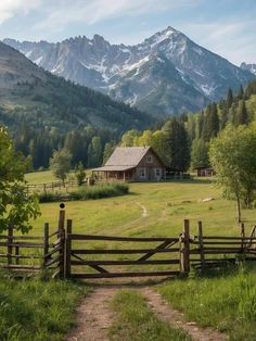 a dirt path leading to a wooden fence with a barn in the distance and mountains in the background