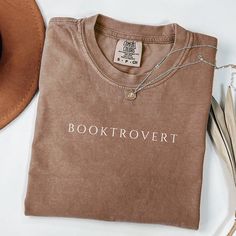 Celebrate your love for reading with this beautifully crafted Comfort Colors shirt designed for true book lovers. Whether you're diving into your next great read or attending a book club meeting, this shirt is the perfect companion. Its soft, durable fabric makes it ideal for cozy reading sessions, while the stylish design showcases your passion for books. This Booktrover shirt also makes a thoughtful gift for fellow bookworms, librarians, or anyone who enjoys getting lost in a good story. Perfe Book Club Merch, Book Club Shirts, Library Shirt, Book Club Shirt, Book Club Meeting, Book Shirt, Gift For Book Lover, Bookclub Gifts, Book Clubs