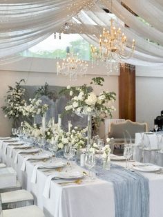 a table set up with white flowers and candles for a formal dinner or wedding reception