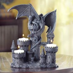 a dragon figurine sitting on top of a table next to some lit candles