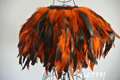 an orange and green feather chandelier hanging from a wire